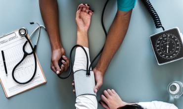 Picture of two people's arms, one is checking the other's blood pressure