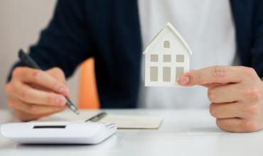 A hand holding a paper house