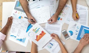 Hands of people shown around a table with research in front of them