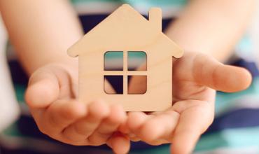 hands holding wooden house