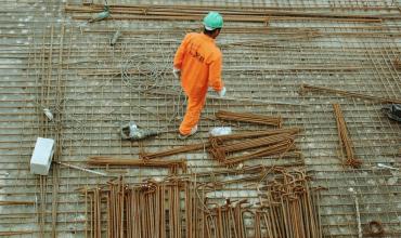 Hurricanes Harvey and Irma Strain Construction Supply A man in an orange suit walking a construction site