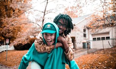 Two people piggybacking on a street