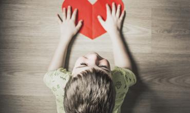 a child holding a paper heart