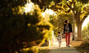 a woman and a child walking on a sidewalk