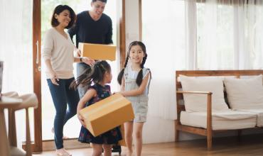 A family walking into their new home with boxes