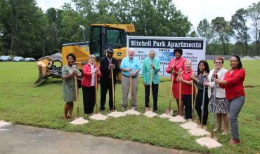 people holding shovels at a groundbreaking ceremony