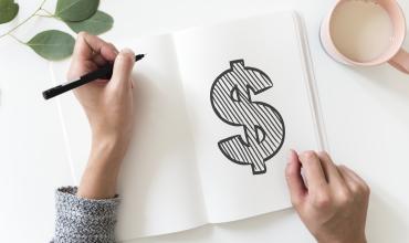 A dollar sign written in a notepad on a desk