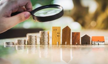 Money and mini apartments under a magnifying glass