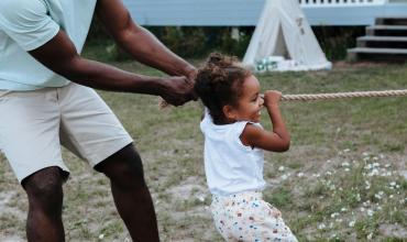 How Affordable Housing Can Benefit Children, Families and Households A dad and his daughter playing tug-of-war in their yard