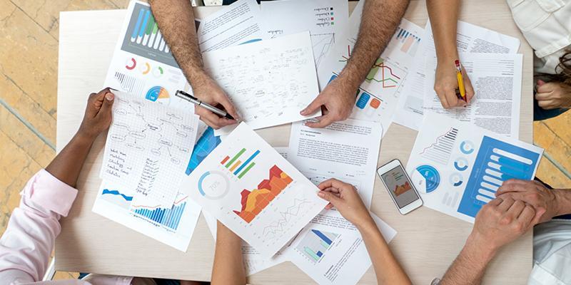 Hands of people shown around a table with research in front of them