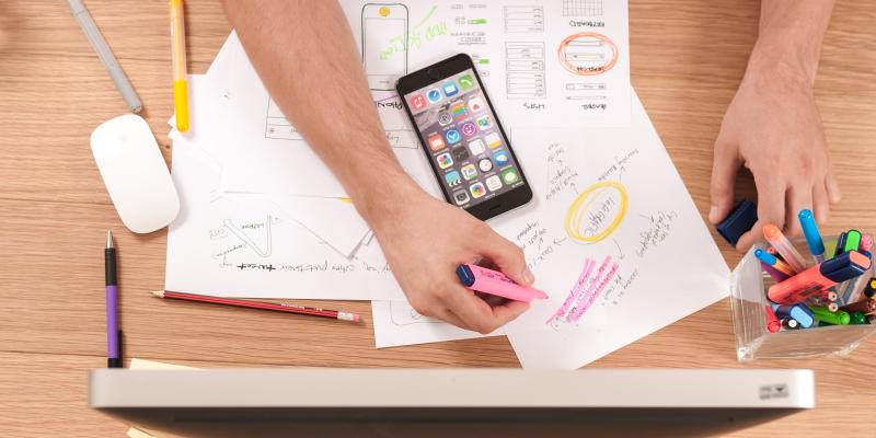 A hand on a table working on a mobile device