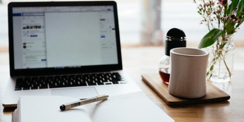 a table with a computer, journal and coffee