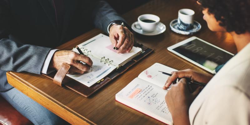 two people sitting at a table with notebooks