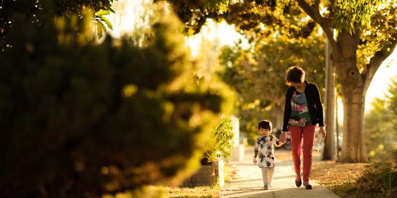 a woman and a child walking on a sidewalk