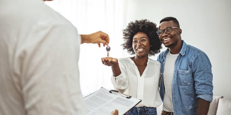 What Home Buyers Should Know About Escrow Two people accepting a key for their home from a real estate agent
