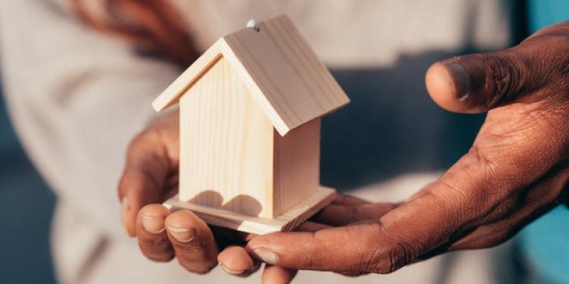 Two people holding a little house in their hands