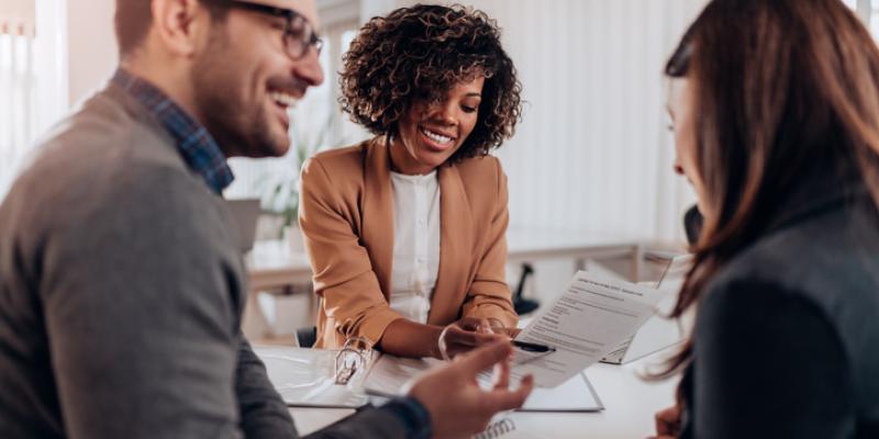 Three people sitting at a table looking at paperwork