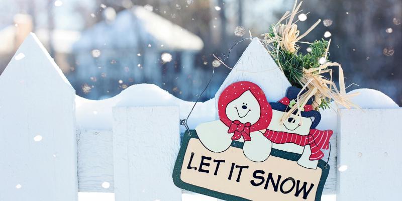 A sign that says Let it Snow on a white fence